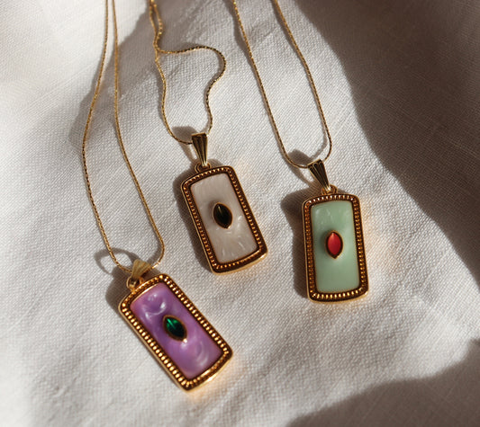 Collana Seed in oro con ciondolo a forma di seme su sfondo bianco
