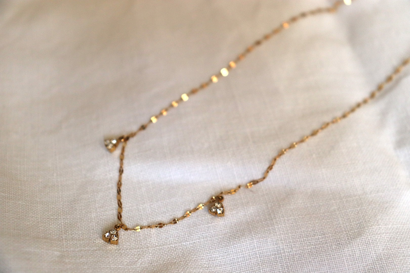 Collana 3 Rays in oro con tre raggi luminosi su sfondo bianco
